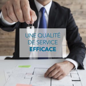 Conseiller immobilier à Allevard remettant les clés d’une maison à ses clients, avec des plans de logement sur son bureau